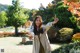 A woman standing in a park with her arms outstretched.