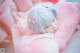 A girl with blue hair laying on a pink pillow.