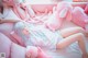 A woman laying on a bed with pink stuffed animals.