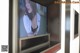 A woman in a white shirt is on a television screen.