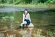 A woman sitting on a rock in the water.