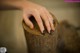 A woman's hand with a black manicure on a tree stump.