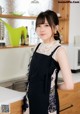 A woman standing in a kitchen wearing a black apron.