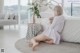 A woman sitting on the floor in front of a bed.