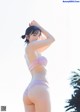 A woman in a pink bikini standing on a beach.