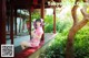 A woman in a pink dress sitting on a bench.