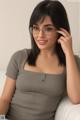 A woman wearing glasses sitting on a white couch.