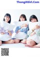 Three young women sitting on a bed with pillows.