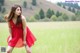 A woman in a red dress standing in a field.