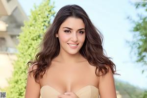 A woman in a beige strapless dress posing for a picture.