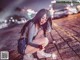 A woman crouching down on the ground with a sparkler in her hand.