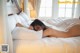 A naked woman laying on a bed with white sheets.